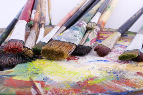 © Adobe Stock Pinsel liegen auf einer Unterlage mit bunten Farbresten. © Adobe Stock