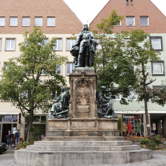 ( Bild: Giulia Iannicelli / Stadt Nürnberg ) Auf dem Theresienplatz thront in seiner ganzen Pracht die Statue Martin Behaims. Nicht ganz so prachtvoll verstecken sich dahinter drei Berg-Ahorne.