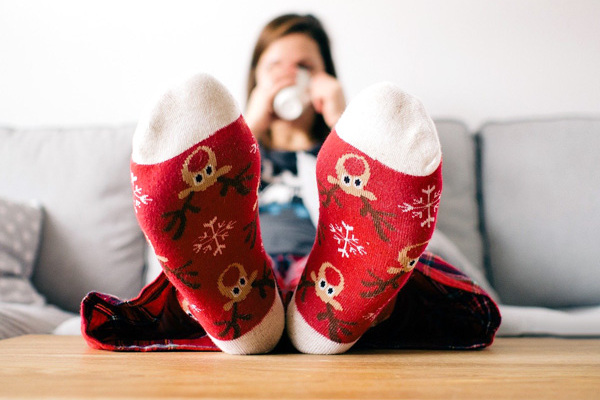 Frau mit Weihnachtssocken auf dem Sofa sitzend.