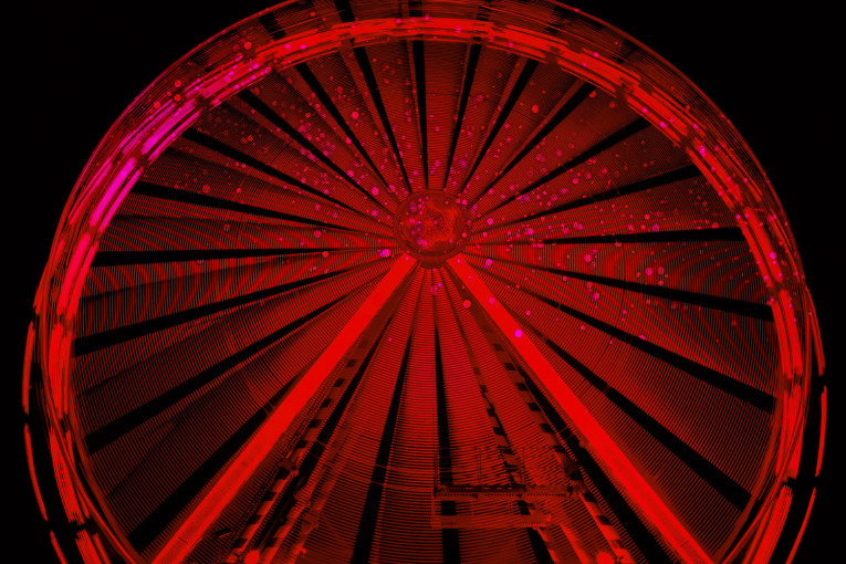 Ein rot beleuchtetes Riesenrad. Es wurde 2023 erstmalig auf dem Nürnberger Jakobsplatz errichtet.