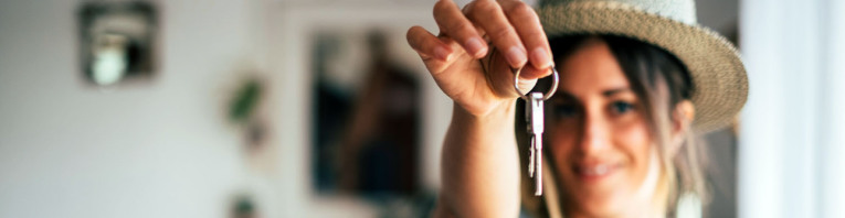 Eine junge Frau mit ihrem Wohnungsschlüssel in ihrem Appartement.